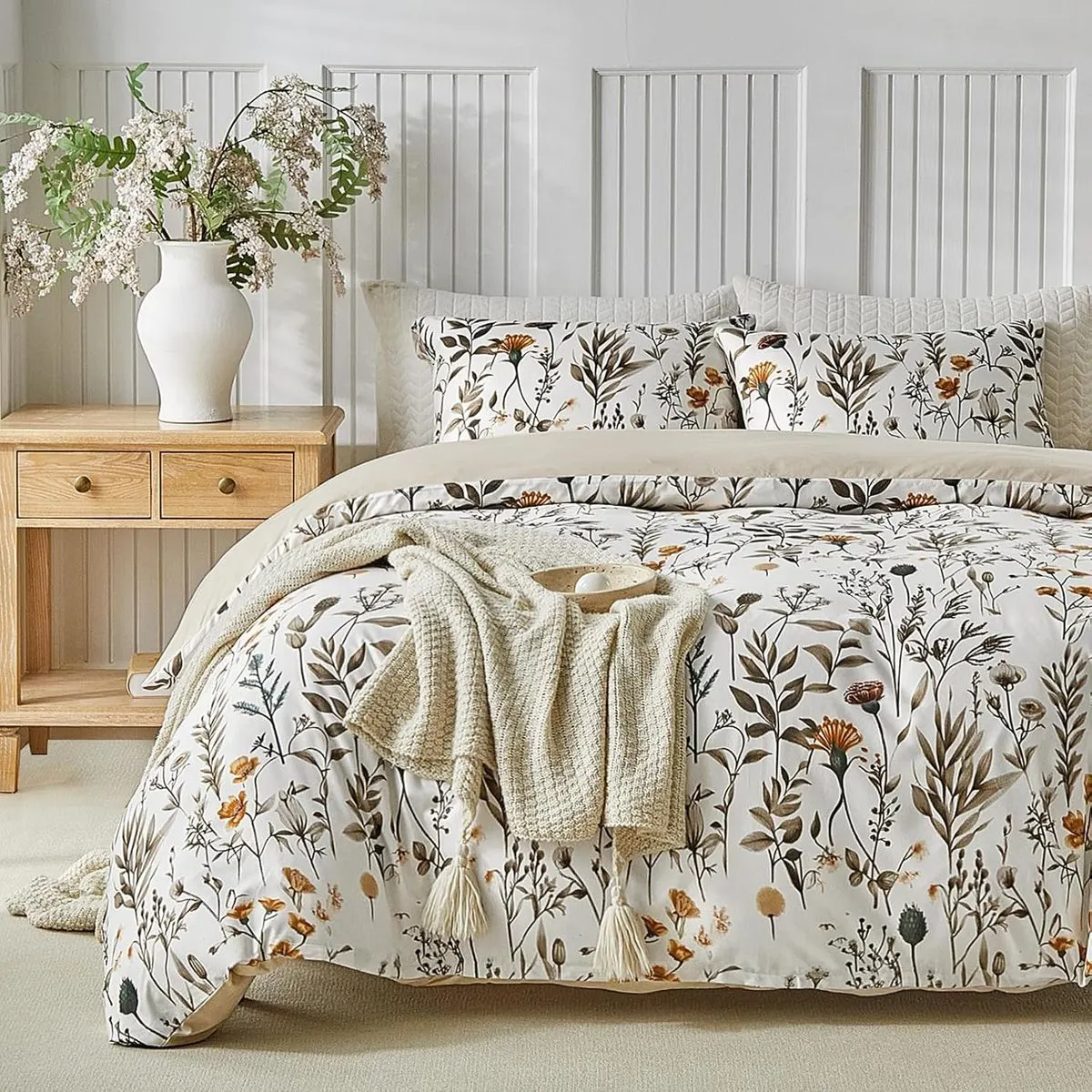 Funda nórdica Lekesky flores y hojas beige sobre una cama